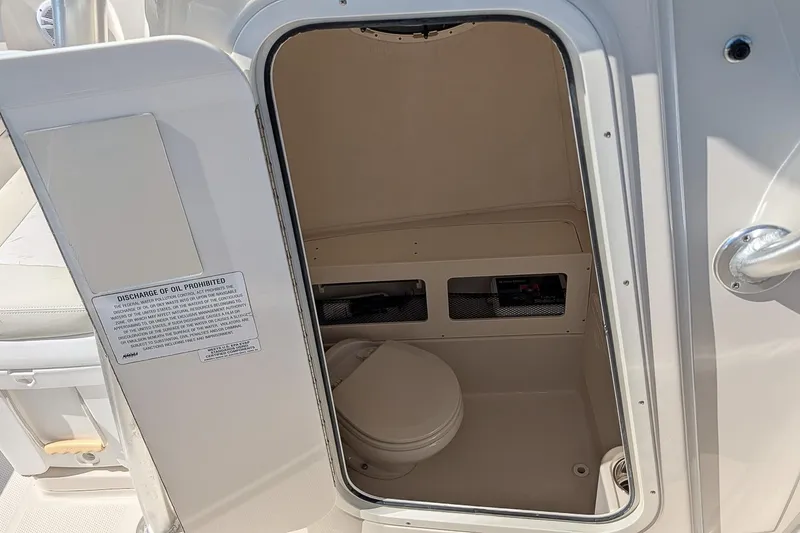 Slide: The Image of 2014 Sailfish 270 CC boat interior with open door revealing compact marine toilet. - 18