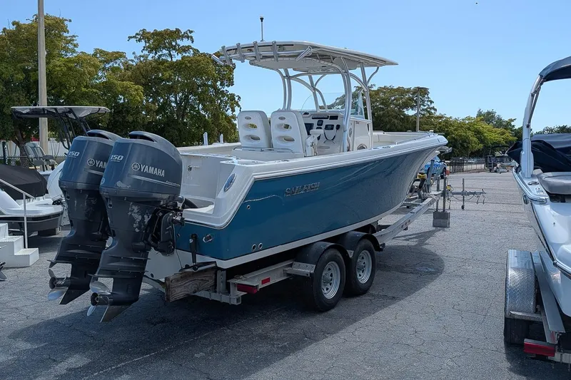 Slide: The Image of 2014 Sailfish 270 CC boat on trailer with twin Yamaha engines in a parking lot. - 2