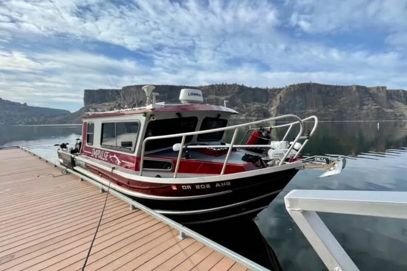 The Image of 2017 Weldcraft 260 Cuddy King docked on a serene lake with scenic cliffs. - 0