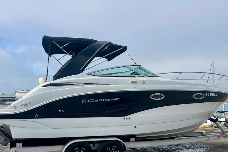 Slide: The Image of 2021 Crownline 264 CR boat on trailer with canopy, docked at marina. - 12