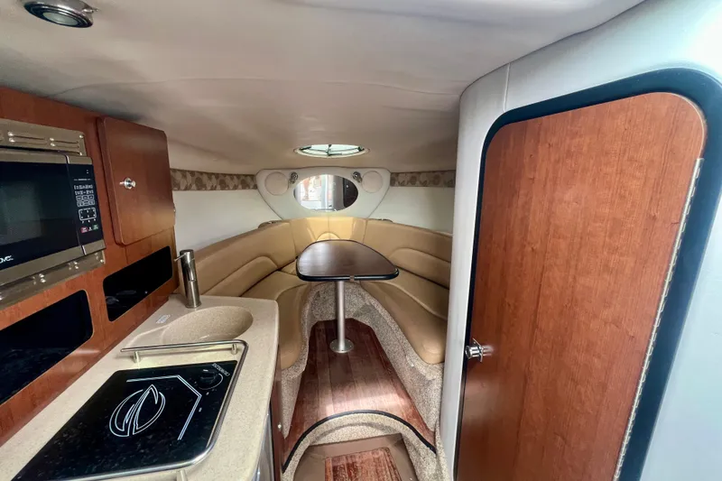 Slide: The Image of 2021 Crownline 264 CR cabin interior with kitchenette, seating area, and wooden finishes. - 16