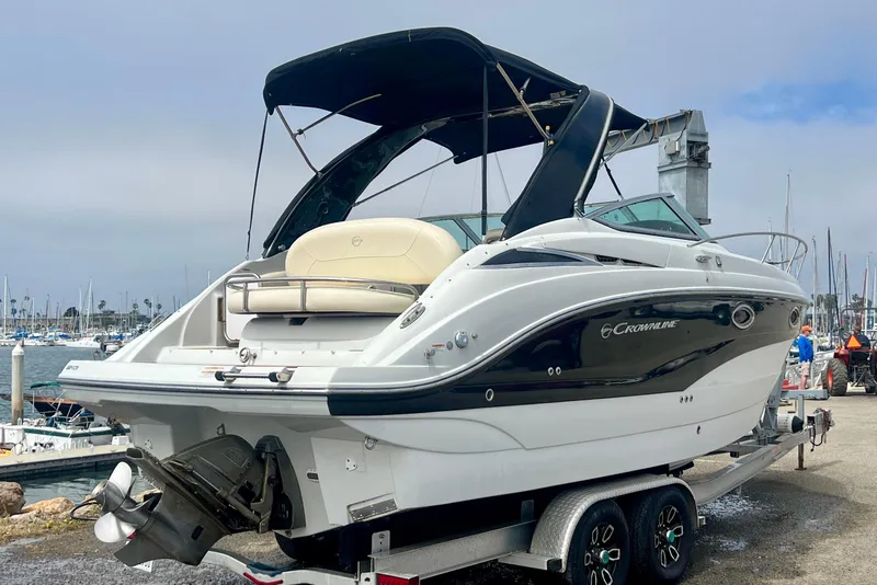Slide: The Image of 2021 Crownline 264 CR boat on trailer at marina, featuring sleek design and black accents. - 2