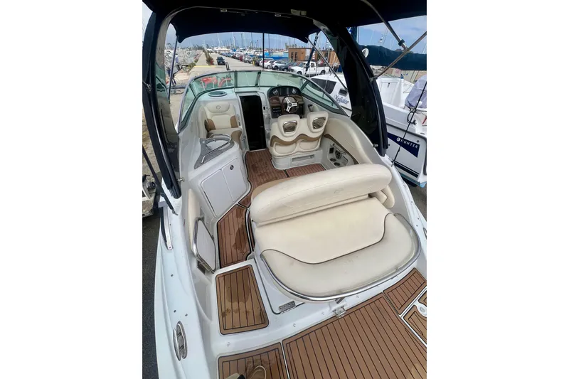Slide: The Image of 2021 Crownline 264 CR boat interior with beige seating and wood flooring, docked at a marina. - 5