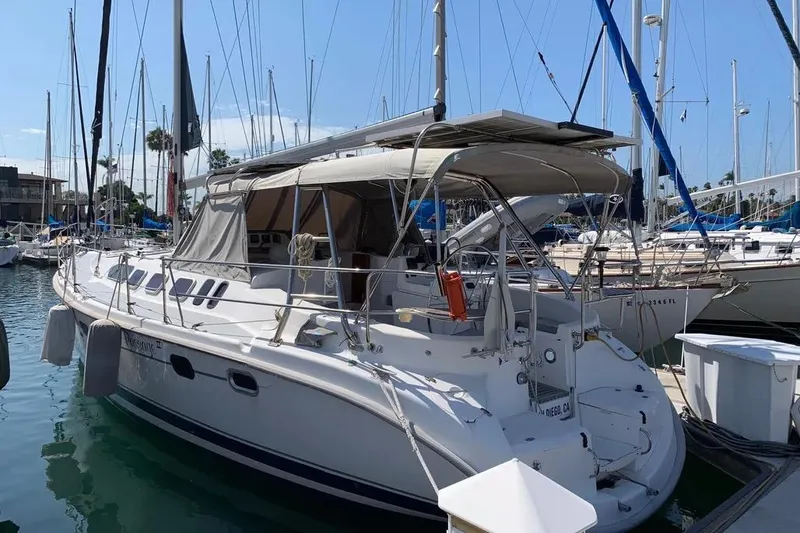 Slide: The Image of 2000 Hunter 460 sailboat docked in marina, featuring spacious deck and canopy. - 2