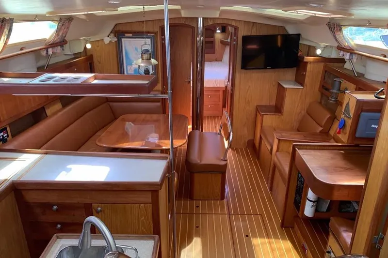 Slide: The Image of Interior of a 2000 Hunter 460 sailboat with wood finish and cozy seating area. - 25