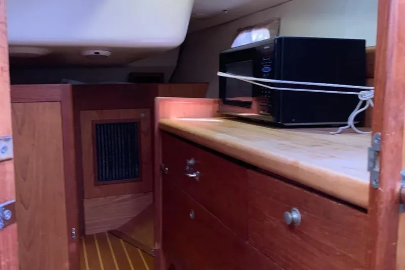 Slide: The Image of Interior of a 2000 Hunter 460 sailboat with wooden cabinetry and a secured microwave. - 30
