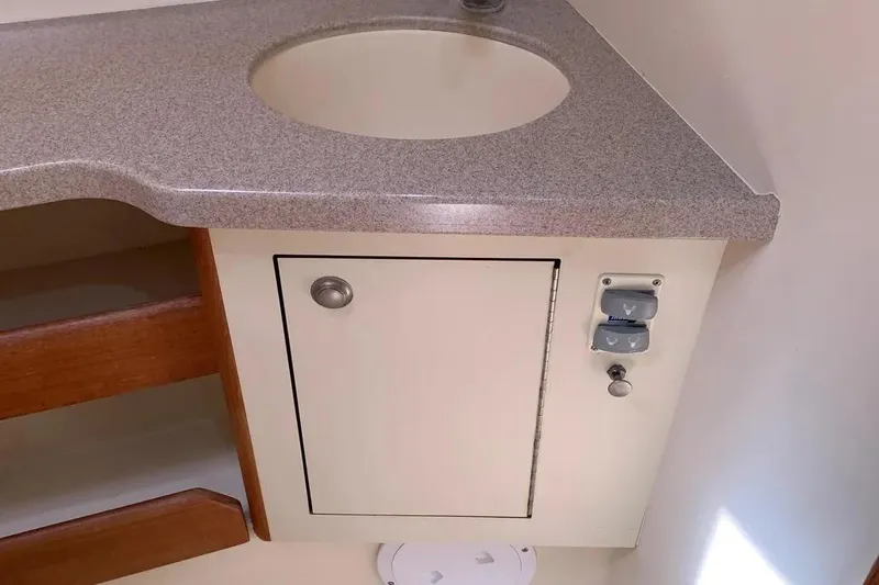 Slide: The Image of Compact bathroom sink area in a 2000 Hunter 460 yacht, featuring storage and controls. - 49