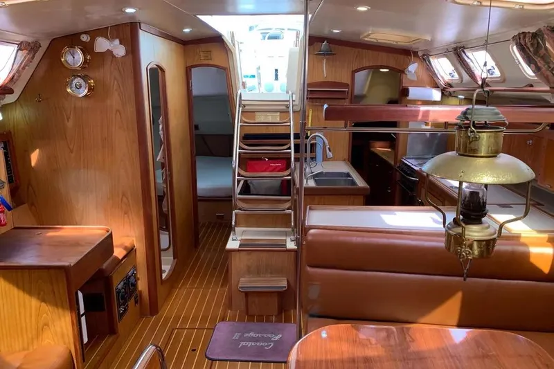 Slide: The Image of Interior of a 2000 Hunter 460 sailboat featuring wood finishes and cozy seating. - 53