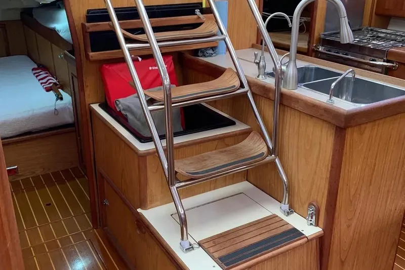 Slide: The Image of Interior of a 2000 Hunter 460 yacht featuring wooden cabinetry and a compact kitchen area. - 54