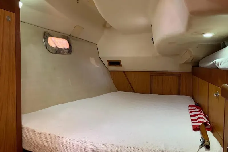 Slide: The Image of Cozy cabin interior of 2000 Hunter 460 sailboat with wooden accents and a small window. - 57