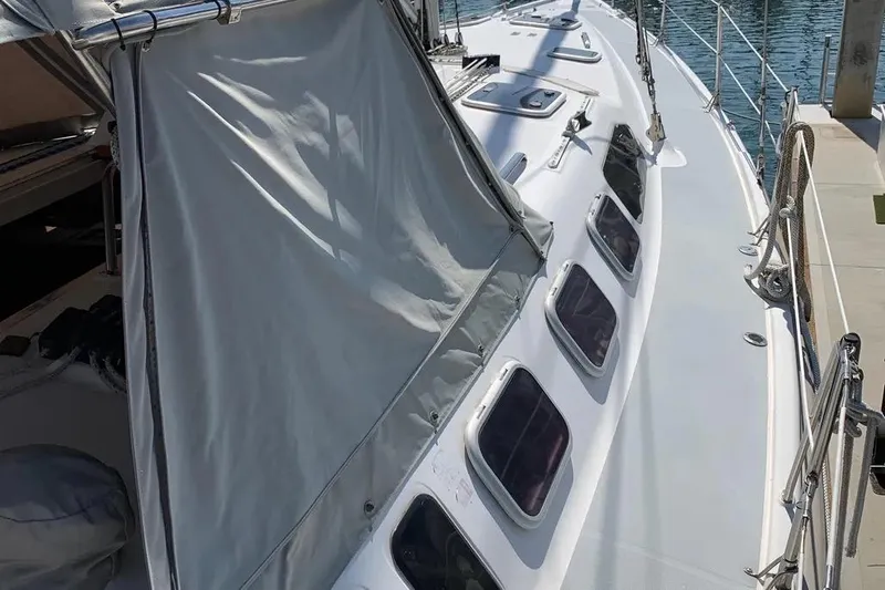 Slide: The Image of Sailboat deck of 2000 Hunter 460 model, featuring multiple windows and docked at a marina. - 9