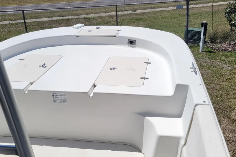 Slide: The Image of 2014 Carolina Skiff 218 DLV boat deck with storage compartments, parked on grass. - 11