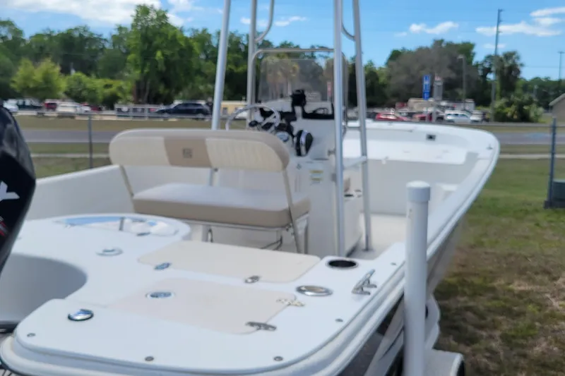 Slide: The Image of 2014 Carolina Skiff 218 DLV boat on display outdoors, featuring seating and steering console. - 12