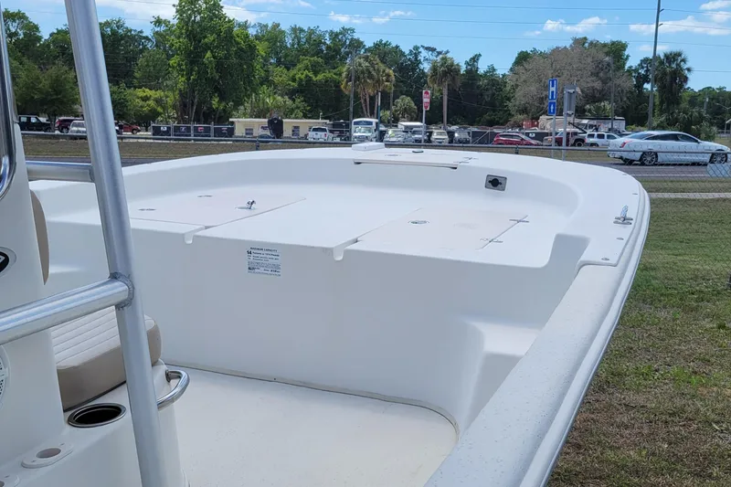 Slide: The Image of 2014 Carolina Skiff 218 DLV boat on grassy area, showcasing spacious deck. - 13