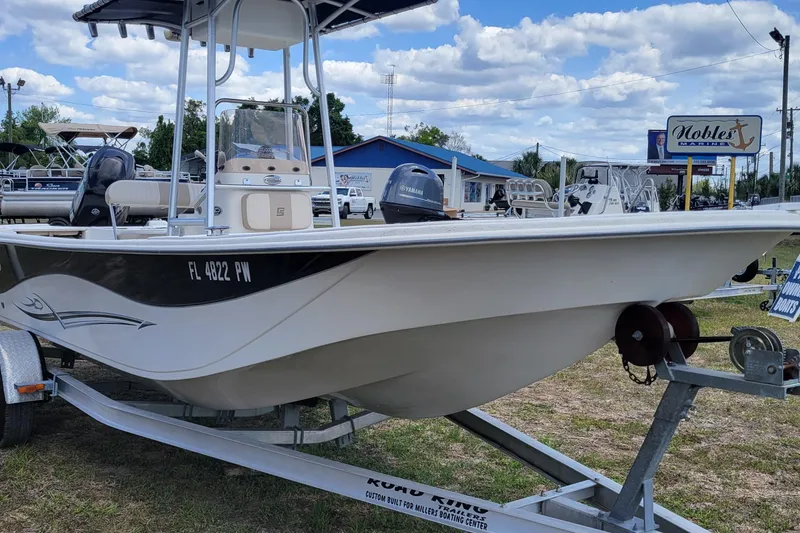 Slide: The Image of 2014 Carolina Skiff 218 DLV boat on trailer at dealership, under blue sky. - 3