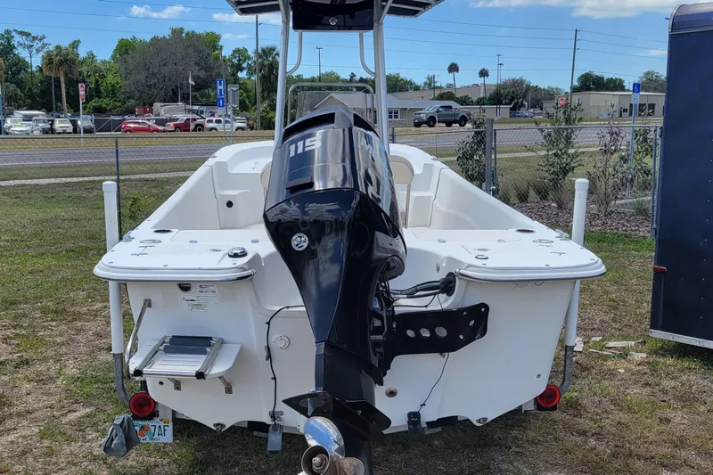Slide: The Image of 2014 Carolina Skiff 218 DLV boat with 115 HP outboard motor, parked outdoors. - 4