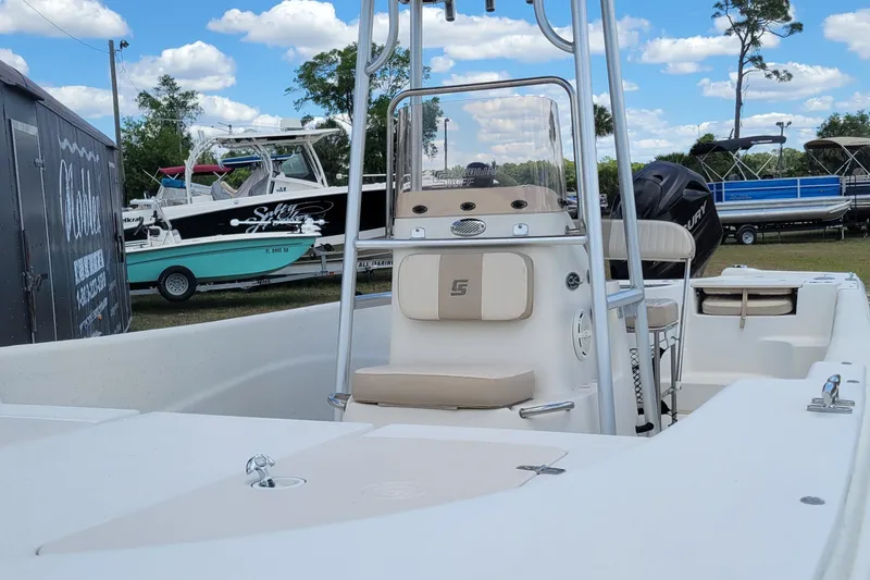 Slide: The Image of 2014 Carolina Skiff 218 DLV boat with center console and seating, displayed outdoors. - 6