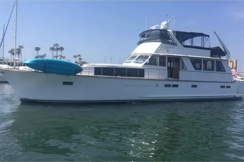 The Image of 1974 Chris-Craft 68 Roamer Flush Deck yacht on calm water, featuring a blue kayak. - 1