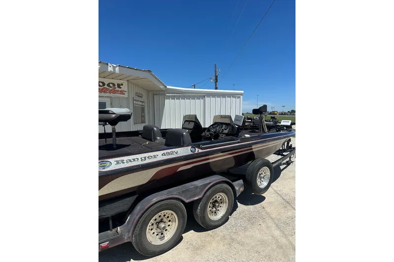 Slide: The Image of 1993 SeaRanger 492V boat on trailer, parked near a building under clear blue sky. - 3