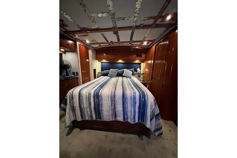 Slide: The Image of Luxurious bedroom interior of 2000 Carver 506 Motor Yacht with striped bedding and wood accents. - 14