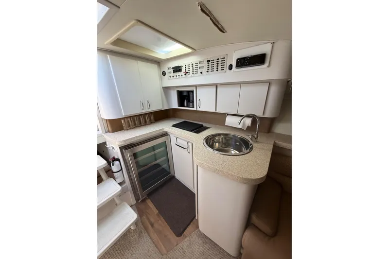 Slide: The Image of 1992 Wellcraft 3400 Gran Sport yacht interior with kitchenette, featuring sink, stove, and storage cabinets. - 17