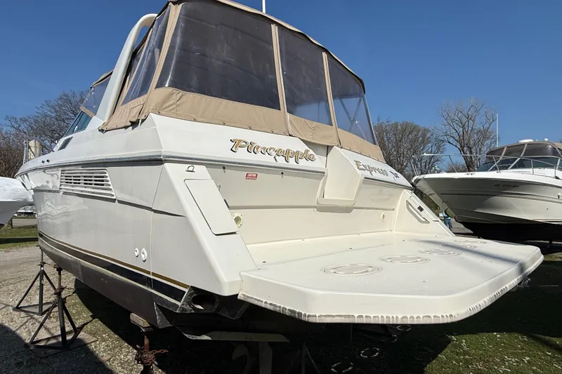 Slide: The Image of 1992 Wellcraft 3400 Gran Sport boat on stands, with beige canopy and "Pineapple Express" text. - 2
