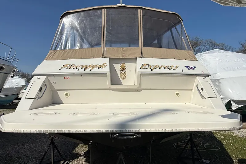 Slide: The Image of 1992 Wellcraft 3400 Gran Sport boat named "Pineapple Express" with tan canopy, docked outdoors. - 3
