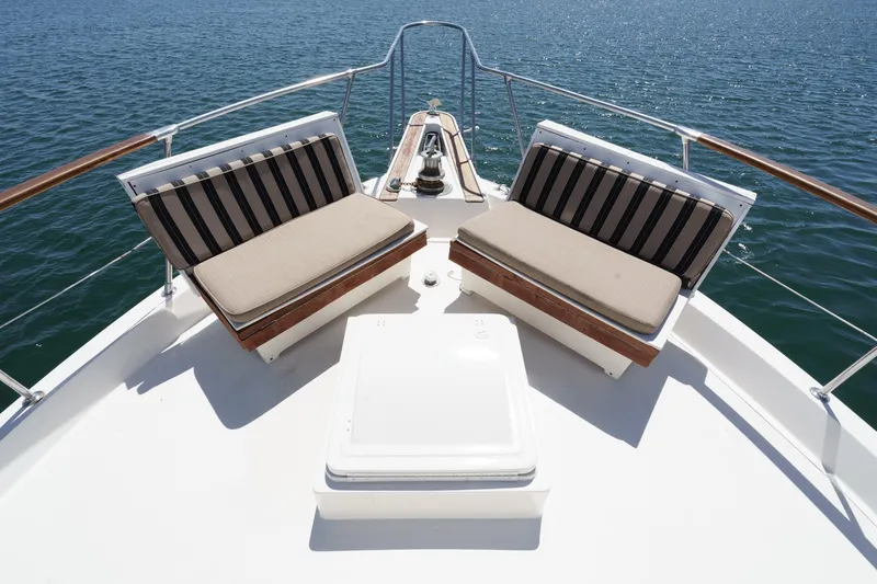 Slide: The Image of 1979 Hatteras 58 Motor Yacht deck with striped seating, overlooking calm water. - 10