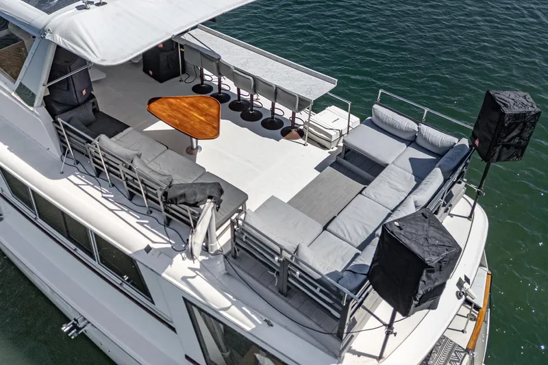 Slide: The Image of 1979 Hatteras 58 Motor Yacht with spacious deck, seating, and bar stools on water. - 15