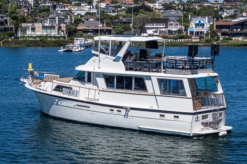 Slide: The Image of 1979 Hatteras 58 Motor Yacht cruising on a scenic waterfront with houses in the background. - 3