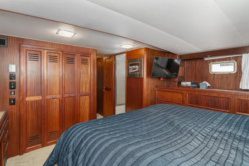 Slide: The Image of Luxurious 1979 Hatteras 58 Motor Yacht bedroom with wood paneling and modern amenities. - 60