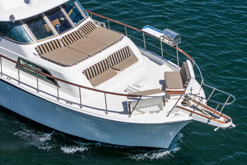 Slide: The Image of 1979 Hatteras 58 Motor Yacht cruising on blue water, featuring spacious deck seating. - 9