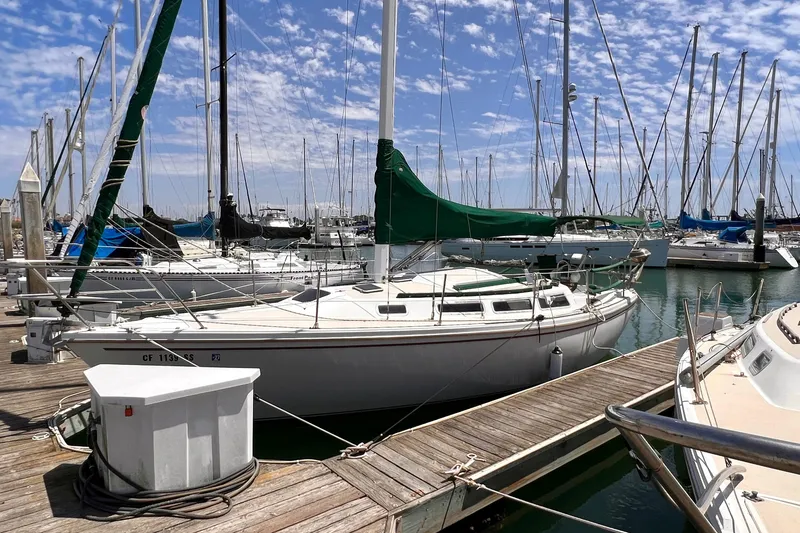 Slide: The Image of 1984 Catalina 30 sailboat docked at marina under a partly cloudy sky. - 2