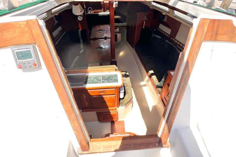 Slide: The Image of Interior view of a 1984 Catalina 30 sailboat, featuring wooden cabinetry and seating. - 21