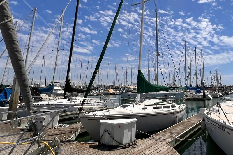 Slide: The Image of Sailboats docked at a marina, featuring a 1984 Catalina 30 under a clear blue sky. - 3
