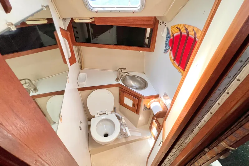 Slide: The Image of Compact bathroom in a 1984 Catalina 30 sailboat, featuring a toilet, sink, and nautical decor. - 40