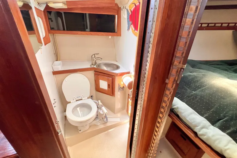 Slide: The Image of 1984 Catalina 30 yacht bathroom with toilet, sink, and wooden cabinetry. - 41