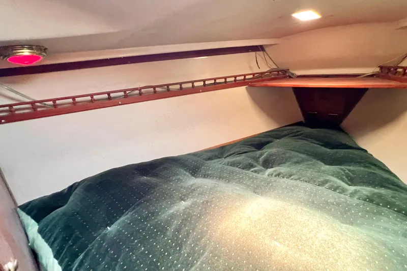 Slide: The Image of Cozy cabin interior of a 1984 Catalina 30 sailboat with a plush green bed. - 44