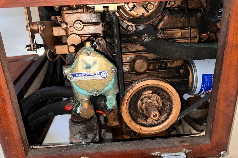 Slide: The Image of Engine compartment of a 1984 Catalina 30 sailboat, featuring mechanical components and hoses. - 49