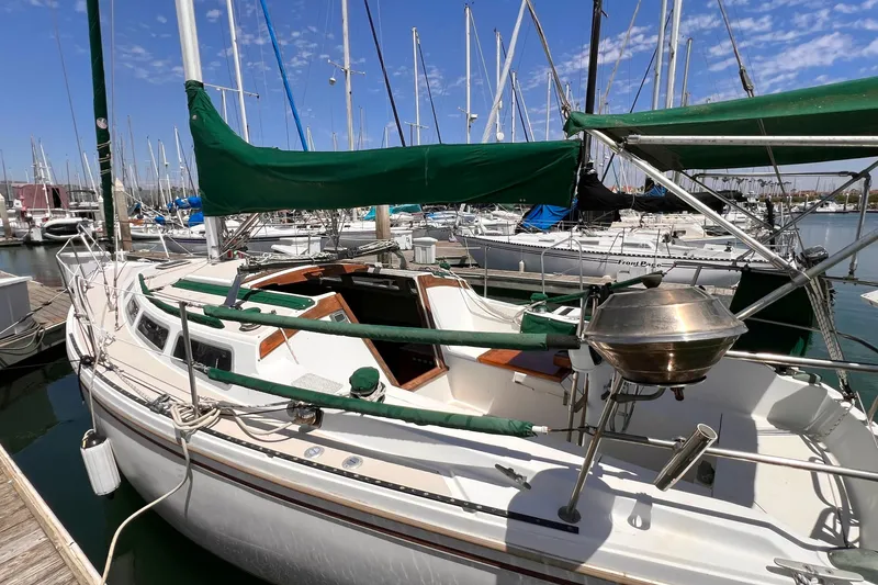 Slide: The Image of 1984 Catalina 30 sailboat docked in marina, featuring green canvas covers and stainless steel grill. - 5