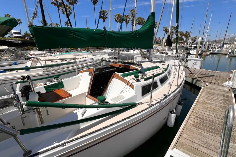 Slide: The Image of 1984 Catalina 30 sailboat docked at marina with green covers and clear sky. - 7