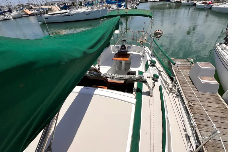 Slide: The Image of 1984 Catalina 30 sailboat docked in marina, featuring green canopy and wooden deck details. - 9