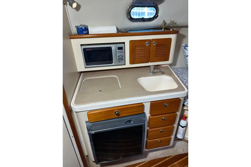 Slide: The Image of Compact galley in 2008 Pursuit OS 335 Offshore boat with microwave, sink, and storage cabinets. - 22