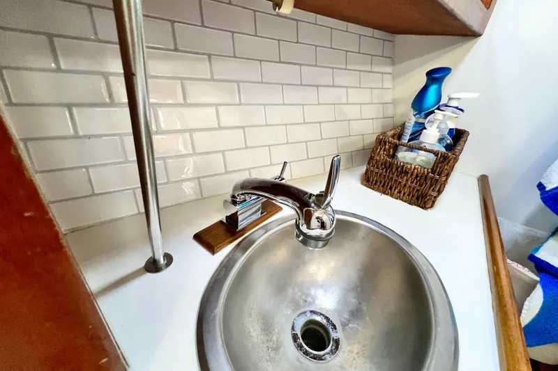 Slide: The Image of Compact sink area in 1985 Catalina 36 yacht with chrome faucet and white tile backsplash. - 46