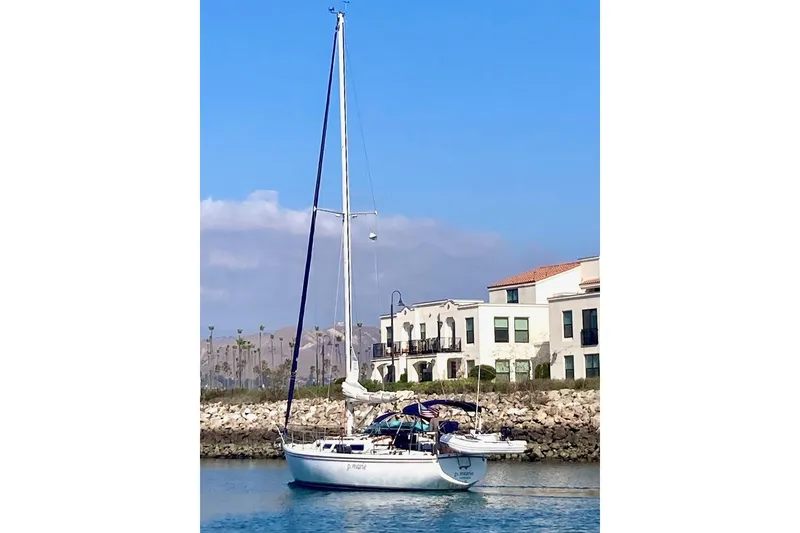 Slide: The Image of 1985 Catalina 36 sailboat docked near waterfront homes under a clear blue sky. - 5