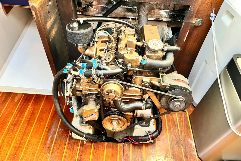Slide: The Image of Engine of a 1985 Catalina 36 sailboat, showcasing mechanical components and wooden flooring. - 55