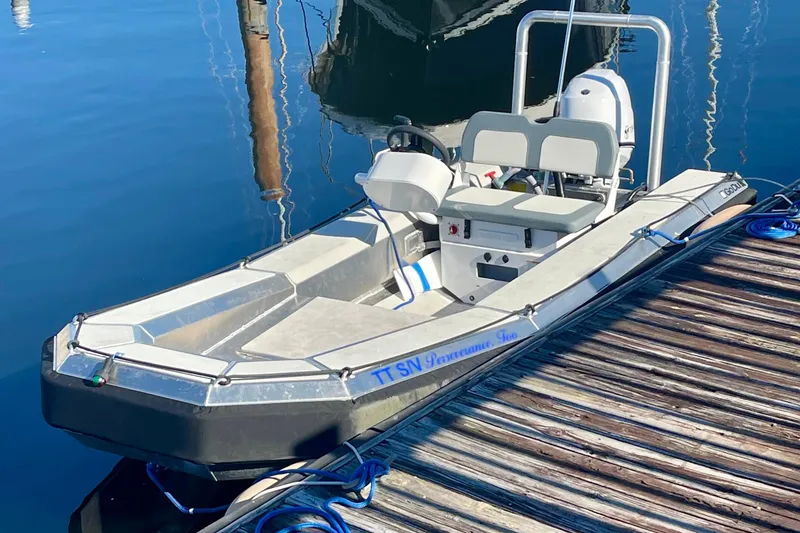 Slide: The Image of Small motorboat docked on calm water, featuring seating and controls. - 10