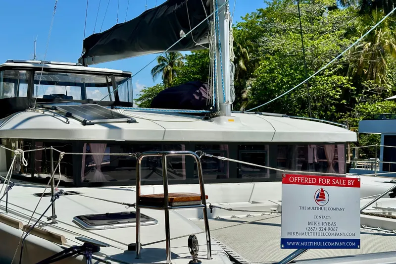 Slide: The Image of 2016 Lagoon 450 S catamaran for sale, docked with lush greenery in the background. - 105