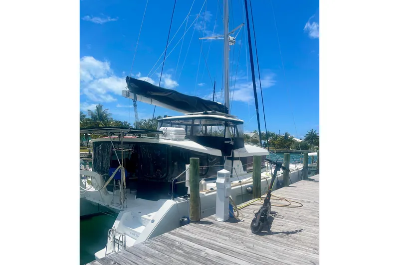 Slide: The Image of 2016 Lagoon 450 S catamaran docked at a marina under a clear blue sky. - 3