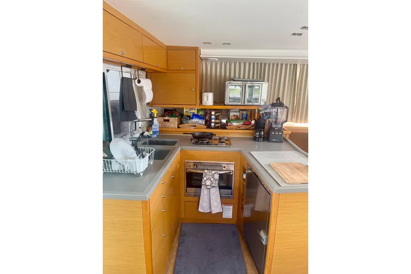 Slide: The Image of Modern kitchen interior on a 2016 Lagoon 450 S yacht, featuring wooden cabinetry and appliances. - 6
